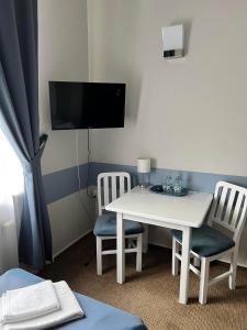 OpocznoにあるHotel Parkのテーブル、椅子2脚、テレビが備わる客室です。
