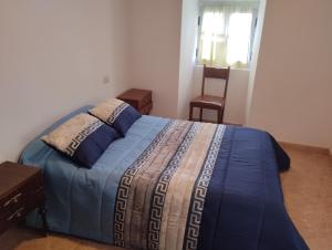 a bedroom with a bed with a blue blanket and a chair at Casa Fuentefria in Ourense
