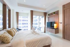 a bedroom with a large white bed and a television at Nam Talay Jomtien Beach - Rooftop Ocean View - Close to Beach, Pool & Gym in Na Jomtien +36 photos
