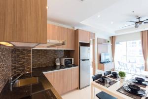a kitchen with wooden cabinets and a counter top at Nam Talay Jomtien Beach - Rooftop Ocean View - Close to Beach, Pool & Gym in Na Jomtien