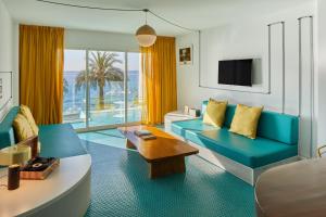 a living room with a blue couch and a tv at Dorado Ibiza - Adults Only in Playa d'en Bossa
