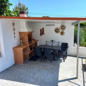 eine Terrasse mit einem Tisch, Stühlen und einem Kamin in der Unterkunft Casa da Ti Emília in Cardigos