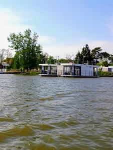 a building sitting on the water in a river at ARKA 2 - Houseboat w centrum Mielna, rower wodny, parking, Wi-Fi in Mielno