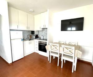 a kitchen with white cabinets and a table and chairs at Ca Mestral Son Bou Urbanización típica menorquina. in Son Bou