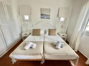 a white bedroom with two beds with towels on them at Ca Mestral Son Bou Urbanización típica menorquina. in Son Bou