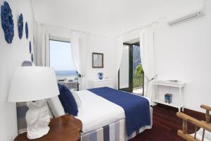 a white bedroom with a bed and a window at La Villa Positano - Luxury villa with private sea access in Positano