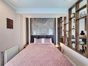 a bedroom with a bed with a pink bedspread at Panorama Deluxe Aparthotel in Cluj-Napoca