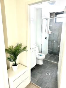 a bathroom with a toilet and a plant in it at Modern 2 bedroom & 2 bathroom apartment with stunning Sydney CBD & Skyline Views! in Liverpool