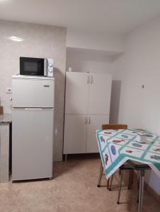 a kitchen with a refrigerator and a table and a microwave at Casa Fuentefria in Ourense
