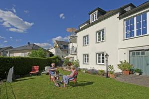 zwei Menschen sitzen an einem Tisch im Garten eines Hauses in der Unterkunft Ferienwohnung Villa Waldesruh in Saarburg