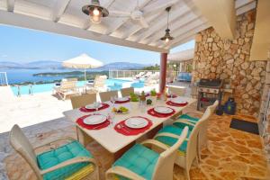a dining room with a table and chairs and a pool at Villa Helios Corfu Kassiopi in Kelliá