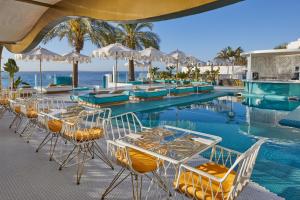 a pool with tables and chairs next to the ocean at Dorado Ibiza - Adults Only in Playa d'en Bossa