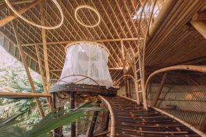 a spiral staircase in a bamboo building with a sign at Hideout Bali in Selat