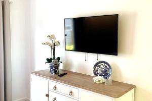 a flat screen tv on a wall above a dresser at Noraville Hamptons Style Beach House in Norah Head
