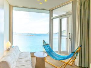 a living room with a hammock in front of a large window at Nichinankaigan Nango Prince Hotel in Nichinan