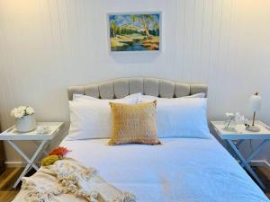 a bedroom with a blue bed with two tables at Noraville Hamptons Style Beach House in Norah Head