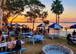 a group of people sitting at tables near the water at Noraville Hamptons Style Beach House in Norah Head
