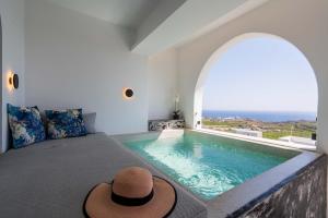a room with a swimming pool with a hat on the bed at Amera Suites in Fira
