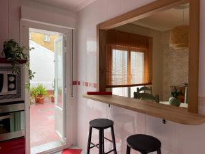 a kitchen with two bar stools and a mirror at Como una casa de campo en la ciudad-Patio y parking gratis in Gijón