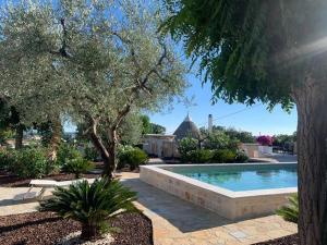 a swimming pool in a yard with trees and a house at Maison dei Trulli in Locorotondo