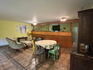 a room with a table and chairs and a kitchen at Erdei Vendégház in Bögöt