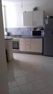 a kitchen with white appliances and a white tile floor at Appartement Tamaris couple mariés in Tamaris