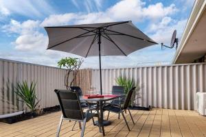 einen Tisch und Stühle mit Sonnenschirm auf einer Terrasse in der Unterkunft Comfortable Central Unit in Geraldton