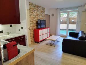 uma cozinha e sala de estar com um sofá e uma televisão em Charmant T2 RD jardin grande terrasse coeur ville plage 2 m clim garage wifi em Sainte-Maxime