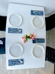 une table blanche avec quatre assiettes et fleurs sur elle dans l'établissement Luxury Apartman ASIA Rijeka, à Rijeka
