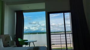 a bedroom with a window with a view of a lake at The River Hotel in Nakhon Phanom