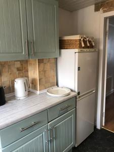 a kitchen with green cabinets and a white refrigerator at The White House - Cheerful 3 Bedroom home in Wigan - Ince - sleeps 7 - parking - Work space - Great motorway links in Ince-in-Makerfield
