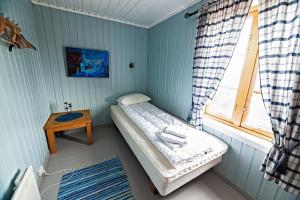 um pequeno quarto com uma pequena cama e uma janela em Rorbu burekka, Stamsund em Stamsund