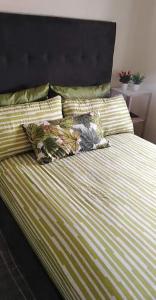 a bed with green and white striped sheets and pillows at Appartement Tamaris couple mariés in Tamaris