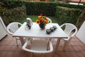 une table et des chaises blanches avec un vase de fleurs. dans l'établissement Salina, à Rosolina Mare