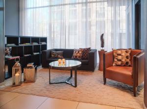 a living room with a couch and a table and a chair at Adina Apartment Hotel Frankfurt Neue Oper in Frankfurt/Main