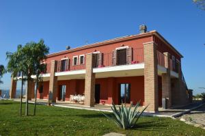 a red building with a palm tree in front of it at Country House Torrenera in Morro dʼOro