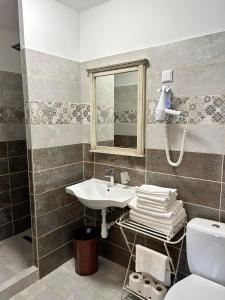 een badkamer met een wastafel, een spiegel en een toilet bij A SZELLŐ 