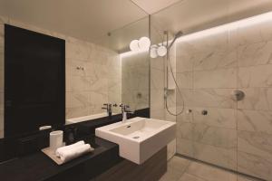a bathroom with a white sink and a shower at Adina Apartment Hotel Hamburg Speicherstadt in Hamburg