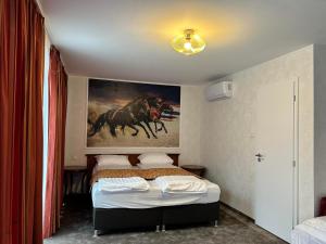 a bedroom with a bed with a painting on the wall at A SZELLŐ 