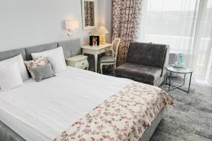 um quarto com uma cama grande e uma cadeira em Continental Forum Oradea em Oradea