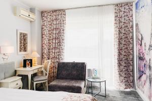 um quarto com uma cama, uma cadeira e uma janela em Continental Forum Oradea em Oradea