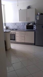 eine Küche mit weißen Geräten und weißem Fliesenboden in der Unterkunft Appartement Tamaris couple mariés in Tamaris