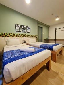 Treeline Urban Inn في كوتا كينابالو: غرفة بسريرين بها شراشف زرقاء وبيضاء