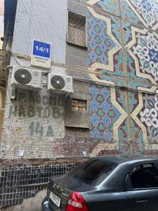 a building with a mosaic wall with a car parked in front at Appartment Tashkent in Tashkent