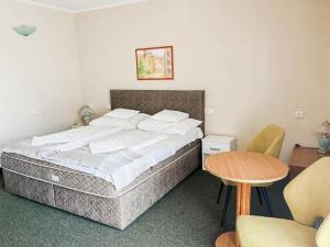 1 dormitorio con 1 cama, mesa y sillas en Hotel Unicornis en Eger