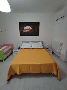 a bedroom with a large bed with a yellow bedspread at B&b Casa Vita COMFORT HOME in Marconia