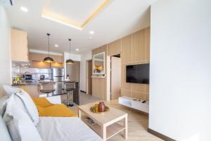 a living room and kitchen with a couch and a table at Calypso Garden Residences by Beringela in Phuket Town
