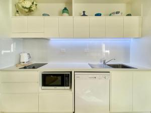 cocina blanca con fregadero y microondas en Rock Salt Villa 1 en Picnic Bay