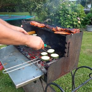 człowiek gotuje jedzenie na grillu w obiekcie Sachserhof Ferienwohnungen w mieście Sachsenburg