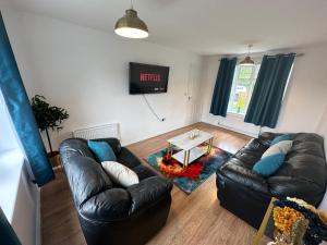 a living room with two leather couches and a table at Trinity's Place in Wythenshawe